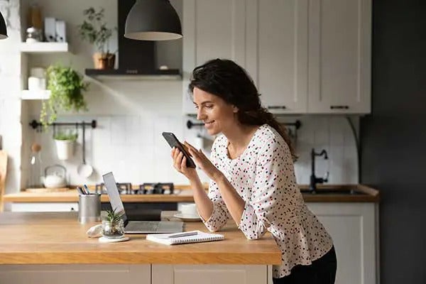 woman uses phone in modern kitchen