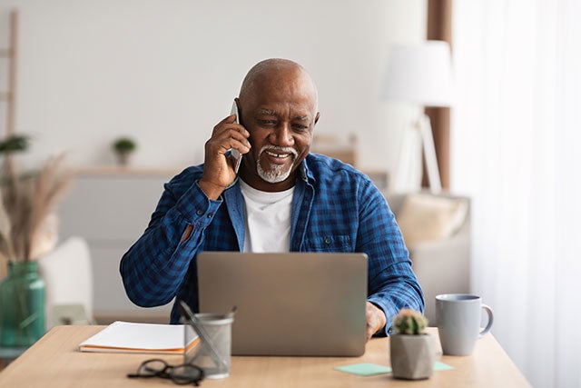 man using phone at computer