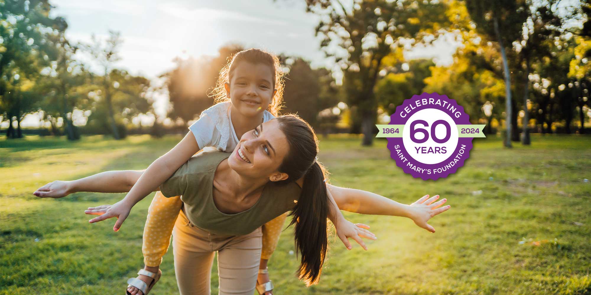 A mother gleefully gives a piggyback ride to her daughter