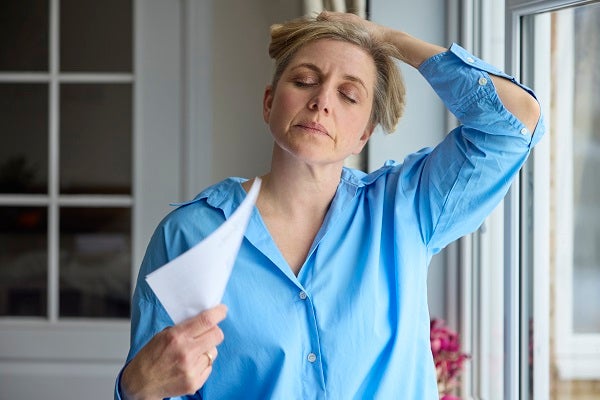 woman fanning herself with a piece of paper
