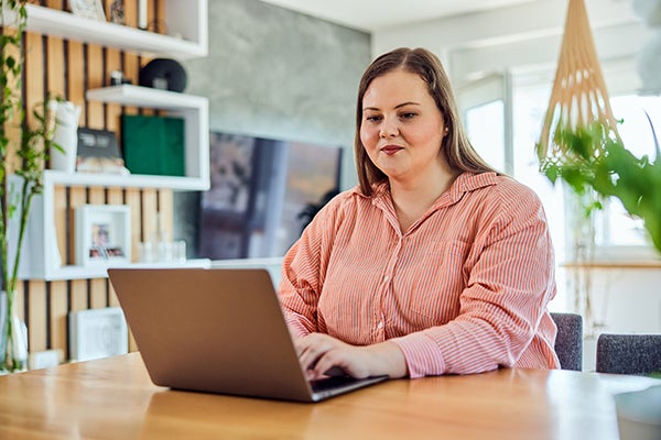 A woman wearing a pink shirt sits at a table and schedules a bariatric surgery consultation