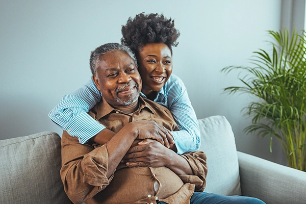 A woman hugs her father from behind
