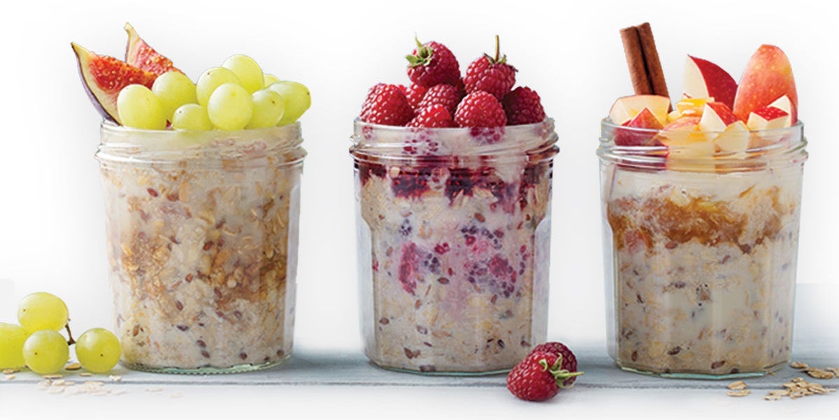 Three glass jars filled with overnight oats, topped from left to right with fig slices, raspberries, and chunks of apple.