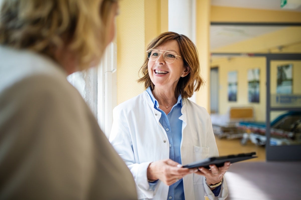 Female doctor smiling and talking to a female patient.