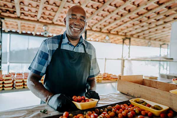 A vendor sells tomatoes at his farmer's market stand