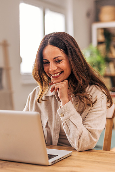 A woman smiles while working on her laptop